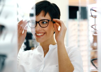 Mujer con gafas nuevas sonriendo en Óptica Jordi Porta.