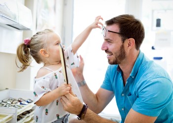 Padre e hija divirtiéndose probándose gafas en Óptica Jordi Porta.