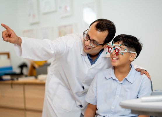 Optometrista realizando examen de visión a un niño con gafas de prueba.