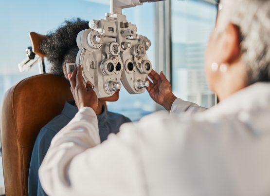 Optometrista realizando un examen de la vista con foróptero a un paciente.