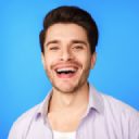 Hombre sonriente con camisa azul sobre fondo azul.